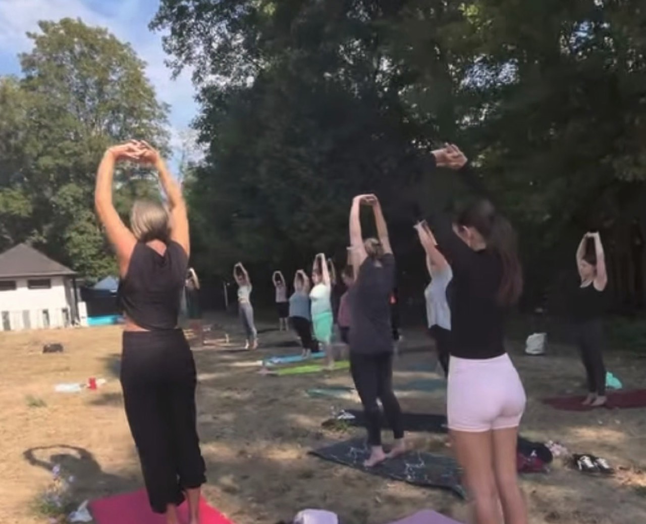 Gruppe von Frauen mit erhobenen Armen bei einer Yoga-Einheit im Abendlicht